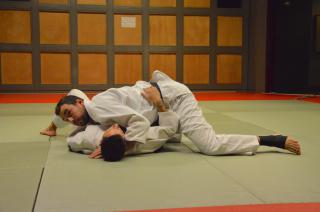 Tori maîtrise Uke par le côté en passant son bras gauche sous la nuque de son adversaire et en bloquant ses jambes avec le bras droit.